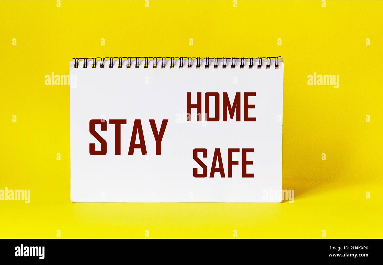 Words Stay Home Stay Safe written on notepad and yellow background. Self Quarantine at Home Concept Staying at home during a pandemic Stock Photo