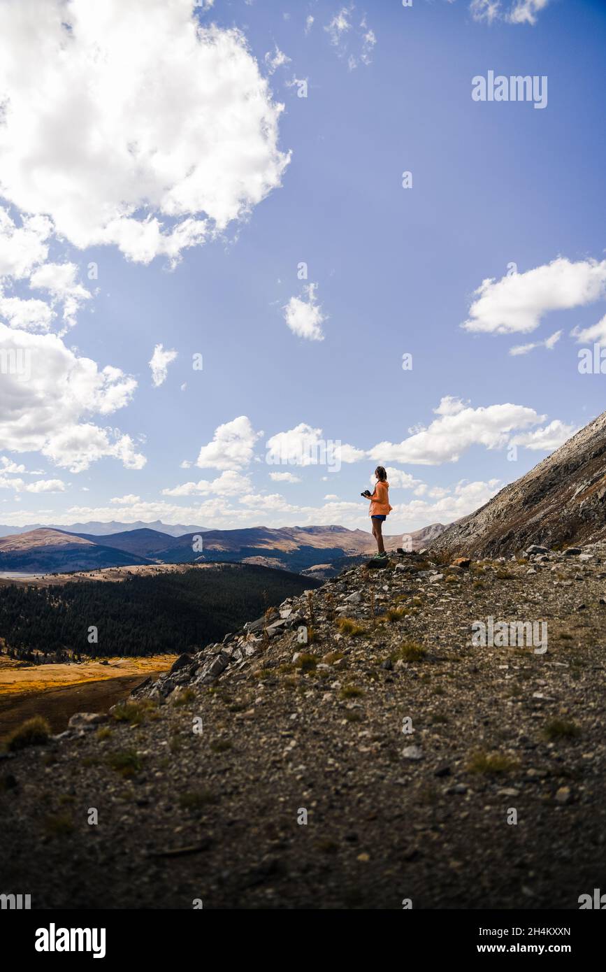 A woman standing on top of a mountain looking over a meadow Stock Photo ...