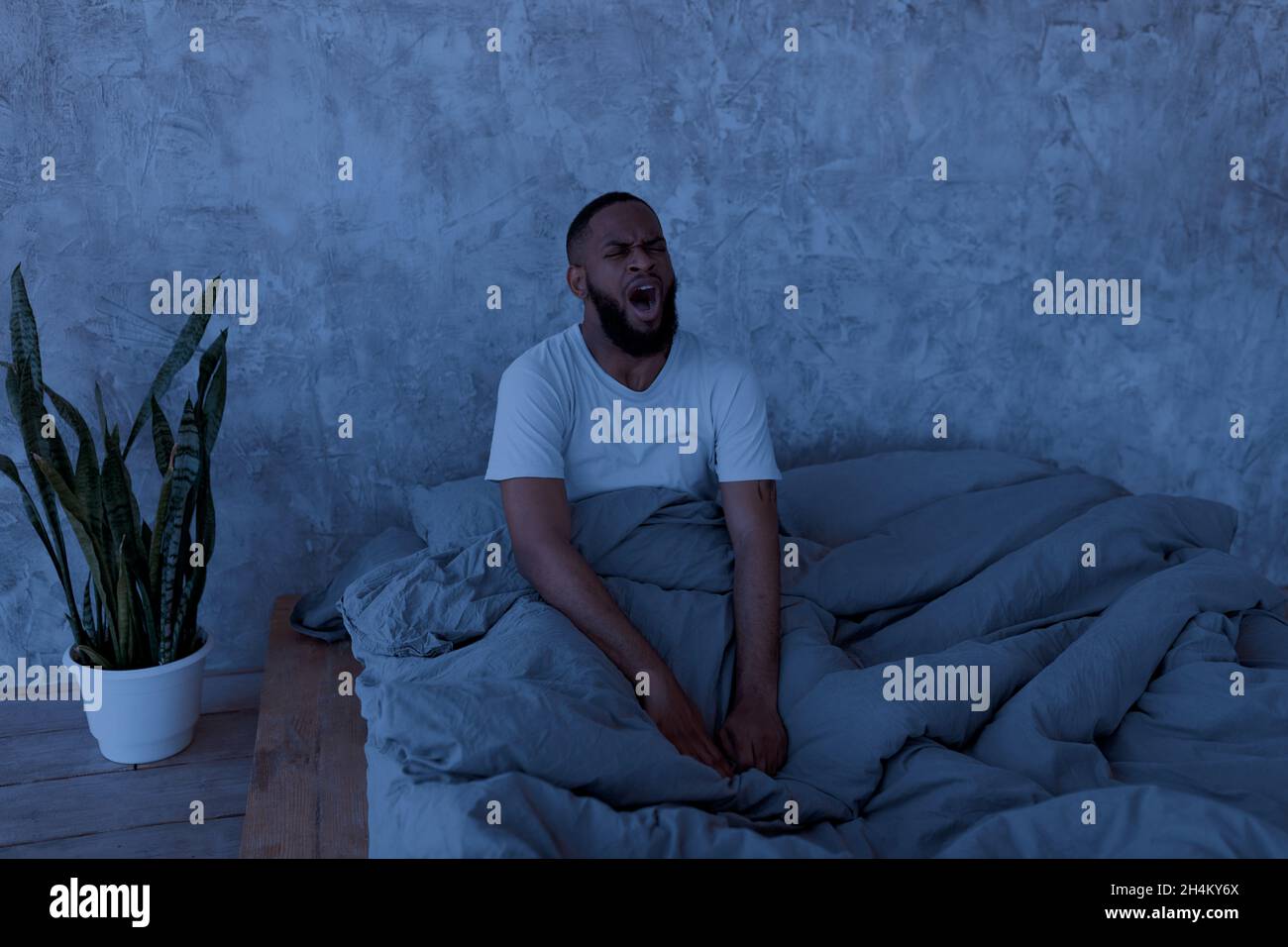 Bad Sleep. Portrait Of Black Guy Waking Up At Night Sitting In Bed With