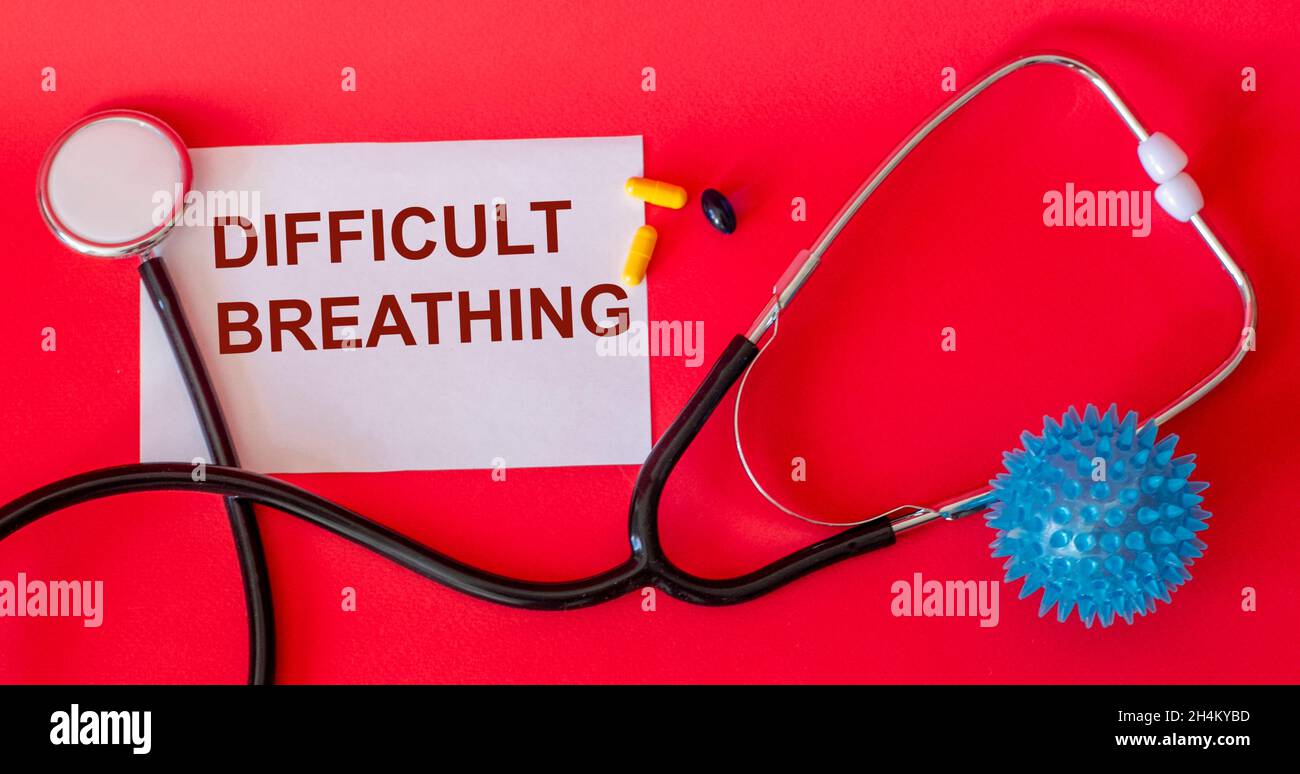 Difficulty breathing - the word is written on white paper and a red background, next to a stethoscope. Respiratory disease symptom Stock Photo
