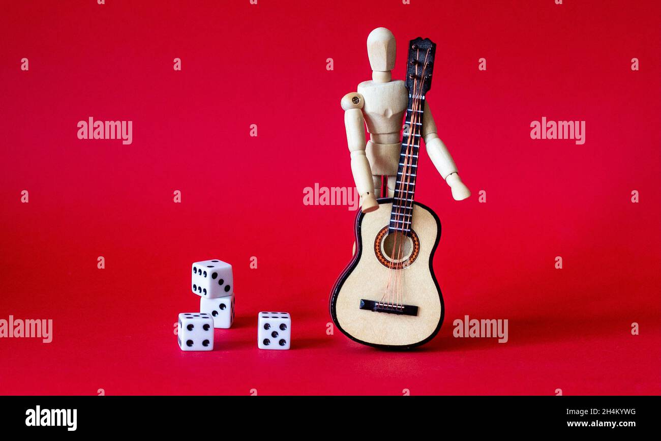 on a red background a wooden man with a guitar near dice Stock Photo