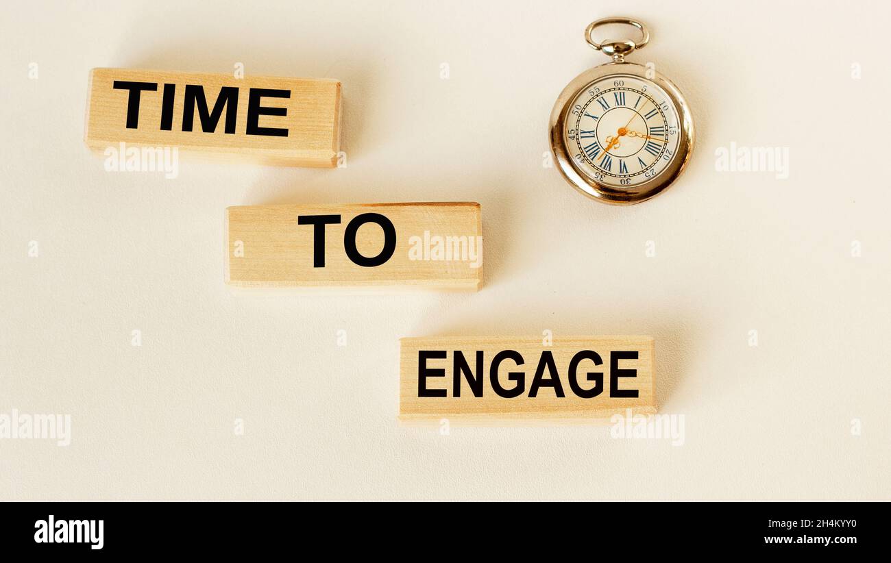 Time to engage text on cubes on a white background, a clock lies next to Stock Photo