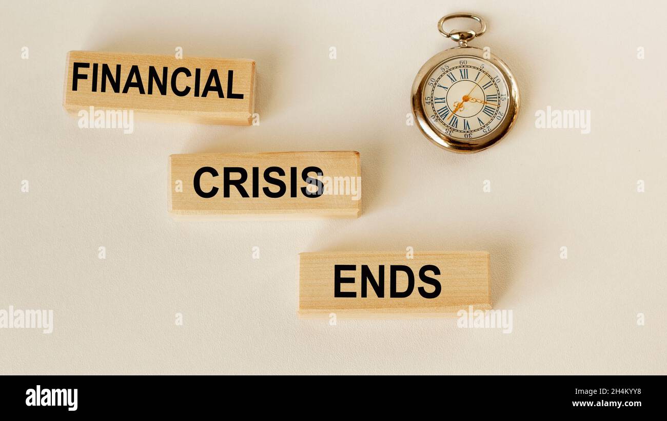 On wooden blocks the text End of crisis and a clock on a white background Stock Photo