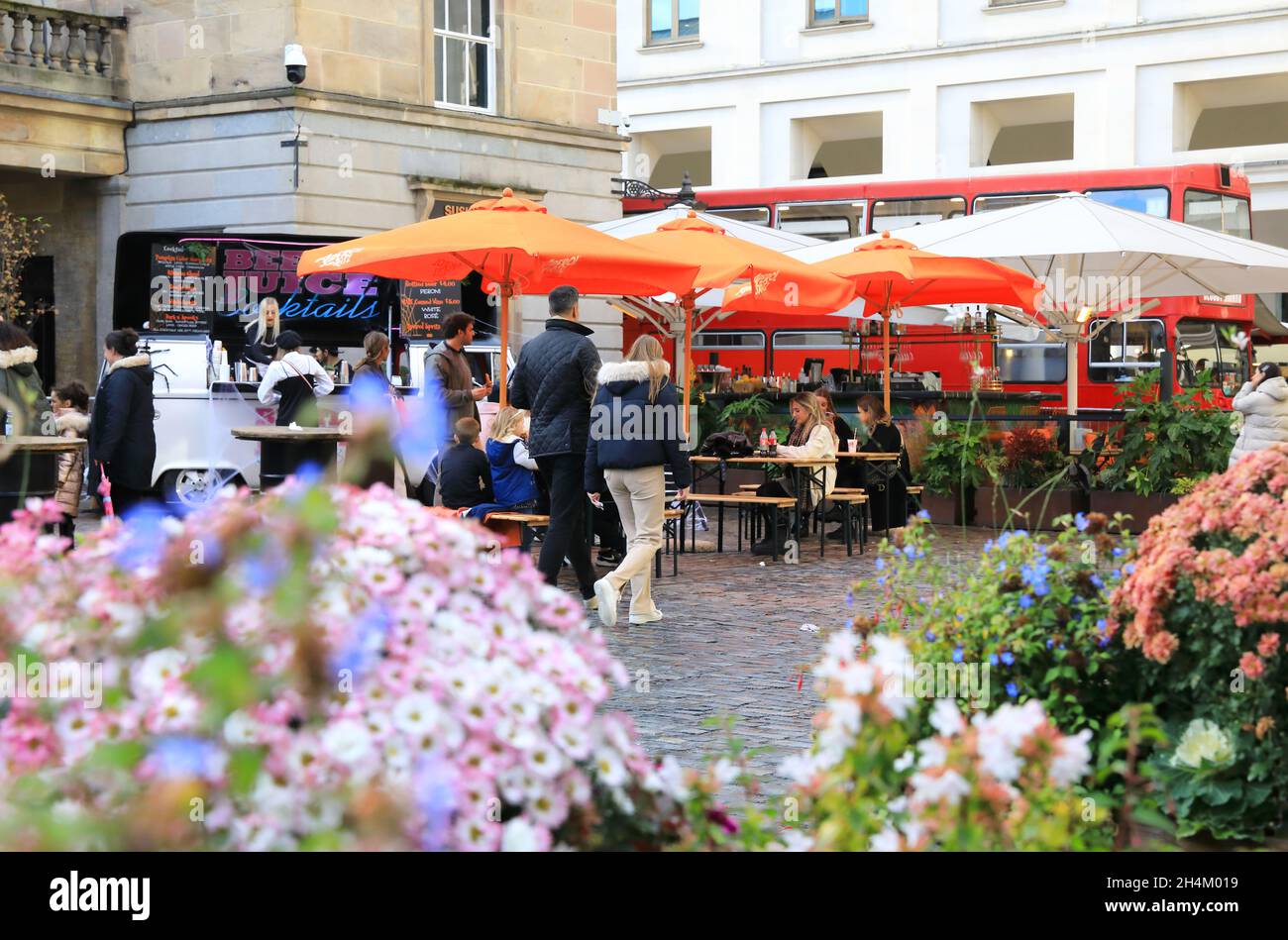 People relaxing in Covent Garden, by autumn flower displays, in London, UK Stock Photo