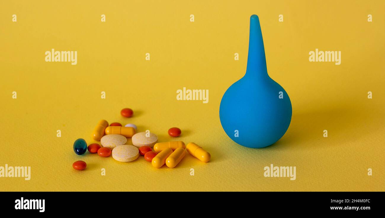 On a yellow background, an enema and pills for diarrhea Stock Photo Alamy