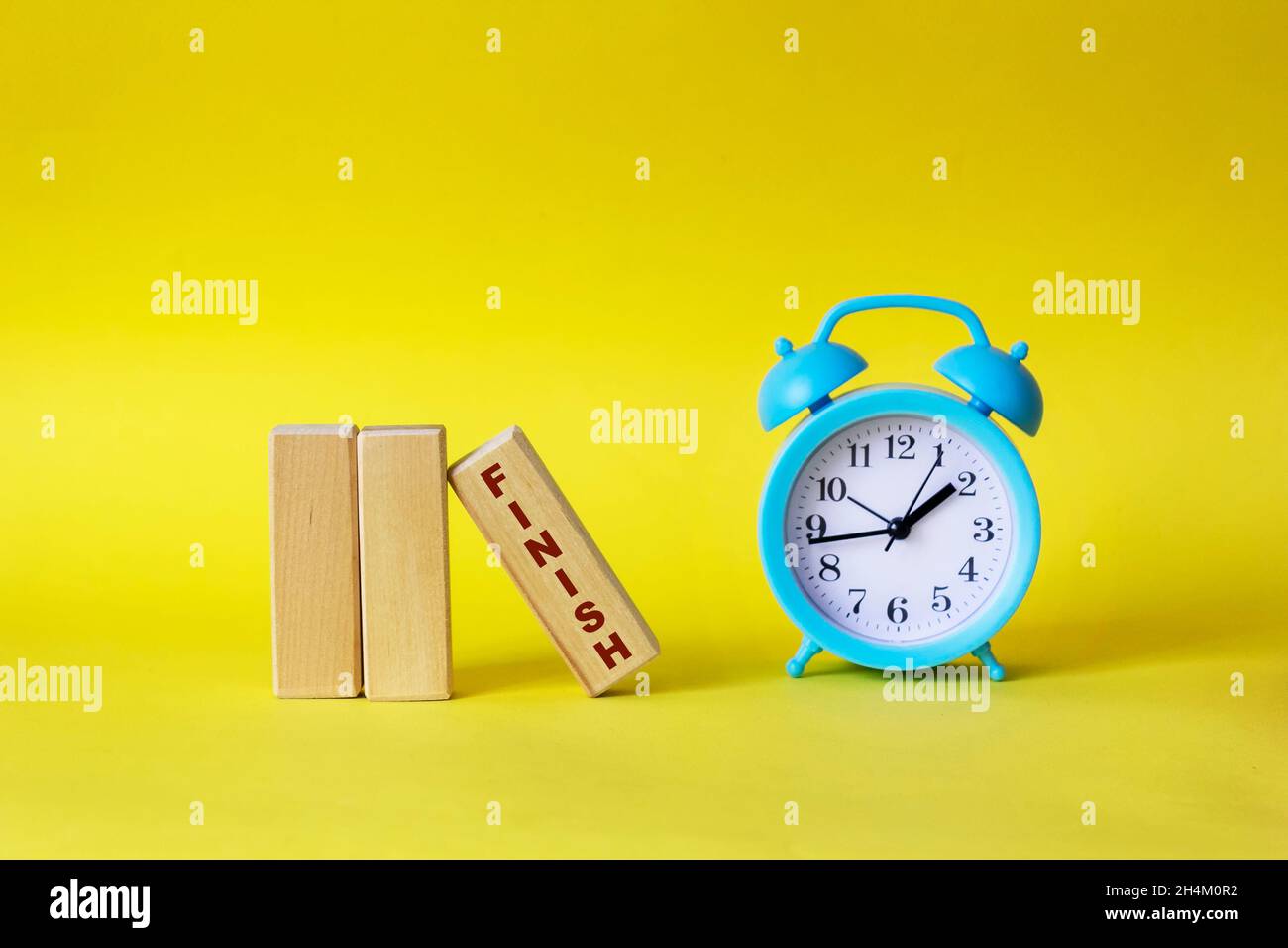 Blocks with the text FINISH on a yellow background, next to a blue alarm clock Stock Photo