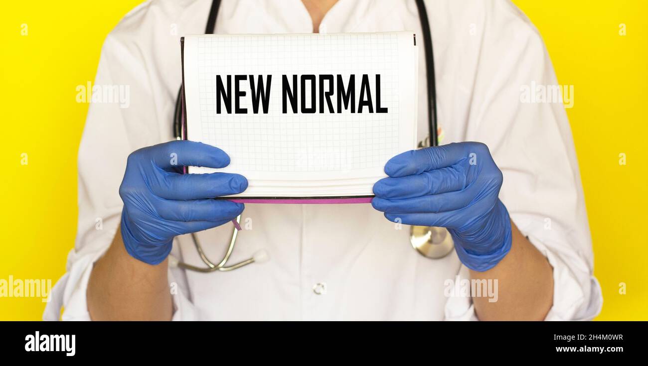 The doctor is holding a notebook with the text New Normal. Medicine concept Stock Photo