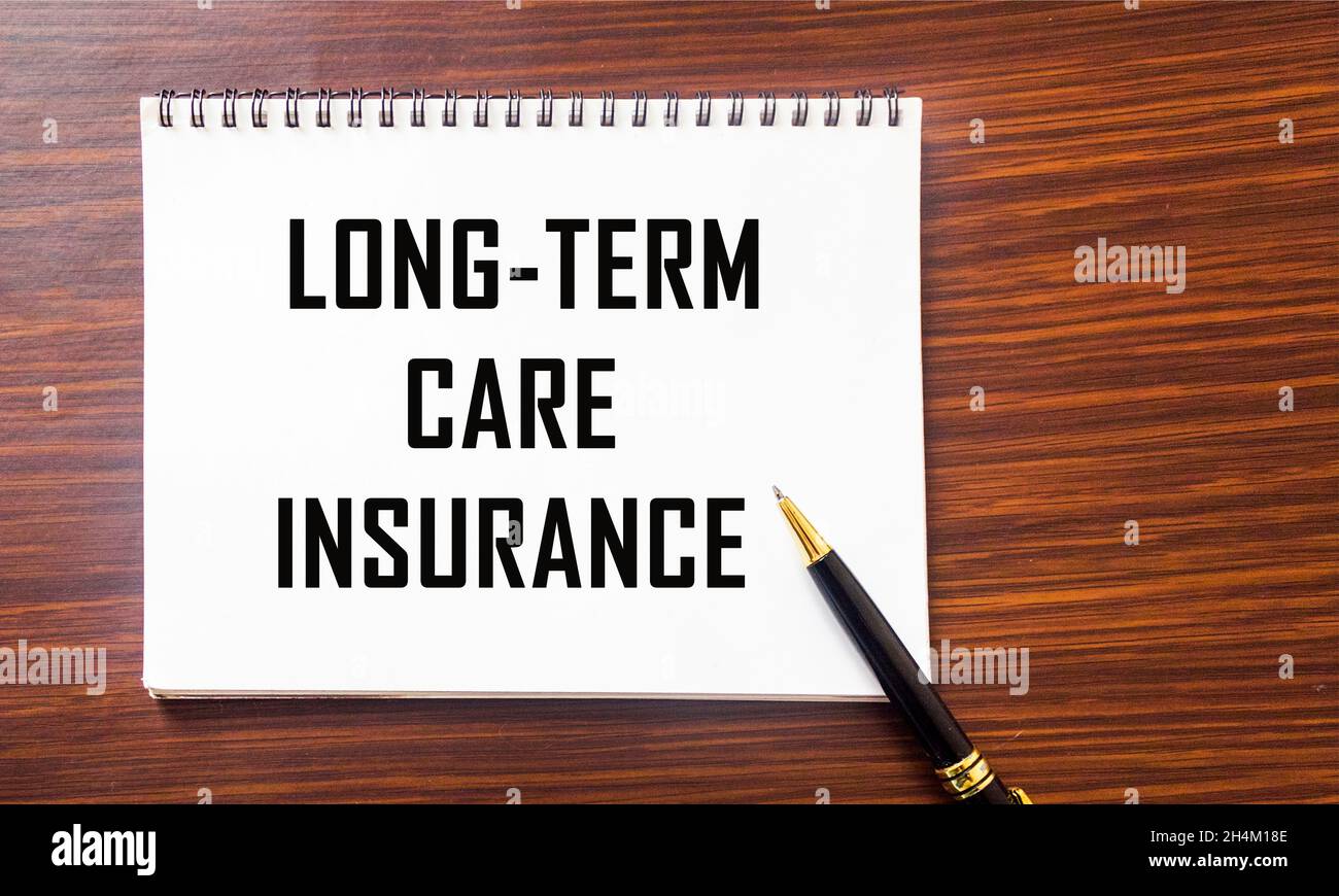 LONG TERM CARE INSURANCE information close-up written on a notepad and a wooden background. Medical concept Stock Photo