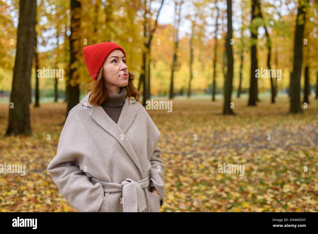 Portrait of woman in wool coat and red hat at autumn park Stock Photo