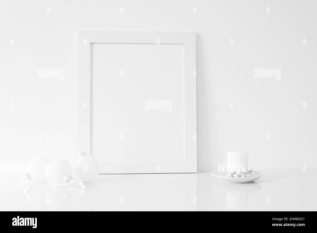 Vertical white blank frame mockup with Christmas candle, and white Christmas decorations. Christmas, winter, festive concept. Copy space. White predom Stock Photo