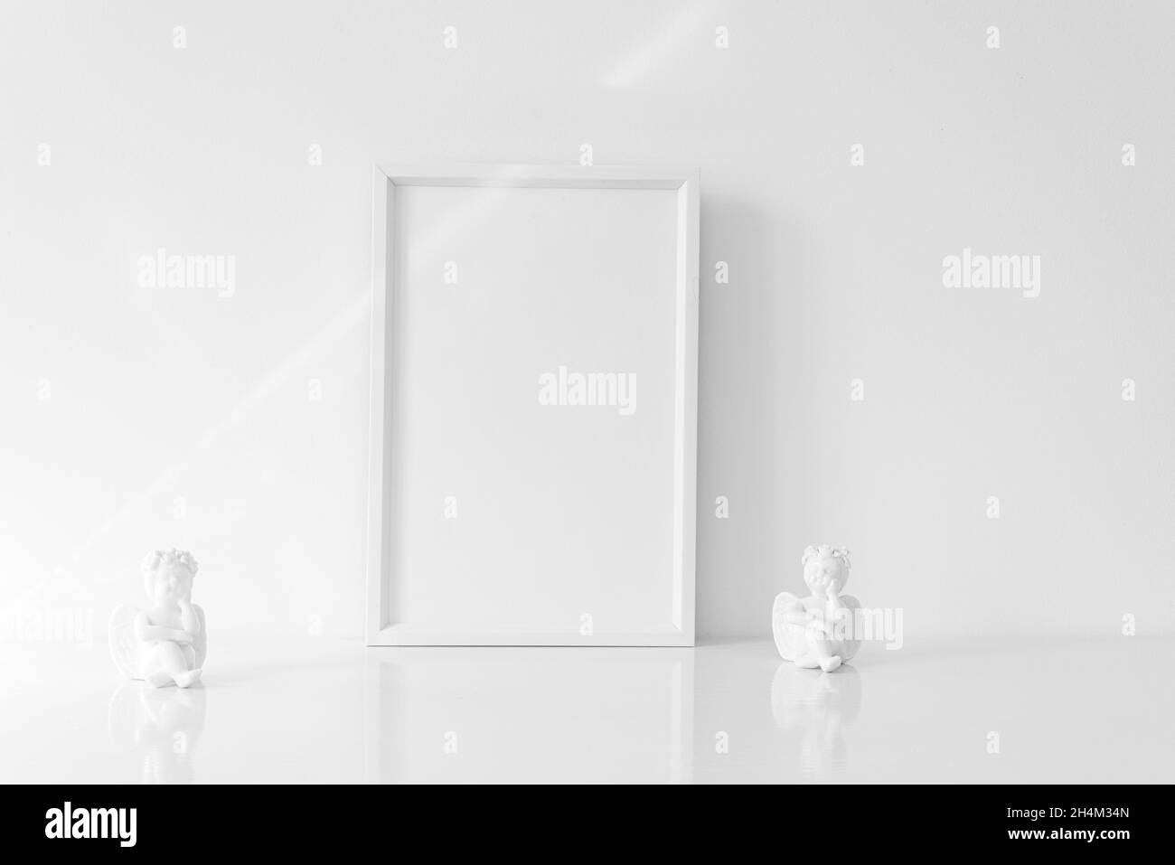 Vertical white blank frame mockup with porcelain Christmas angels. Wedding scene. Christmas, Valentine's day concept. Copy space. White predominance. Stock Photo