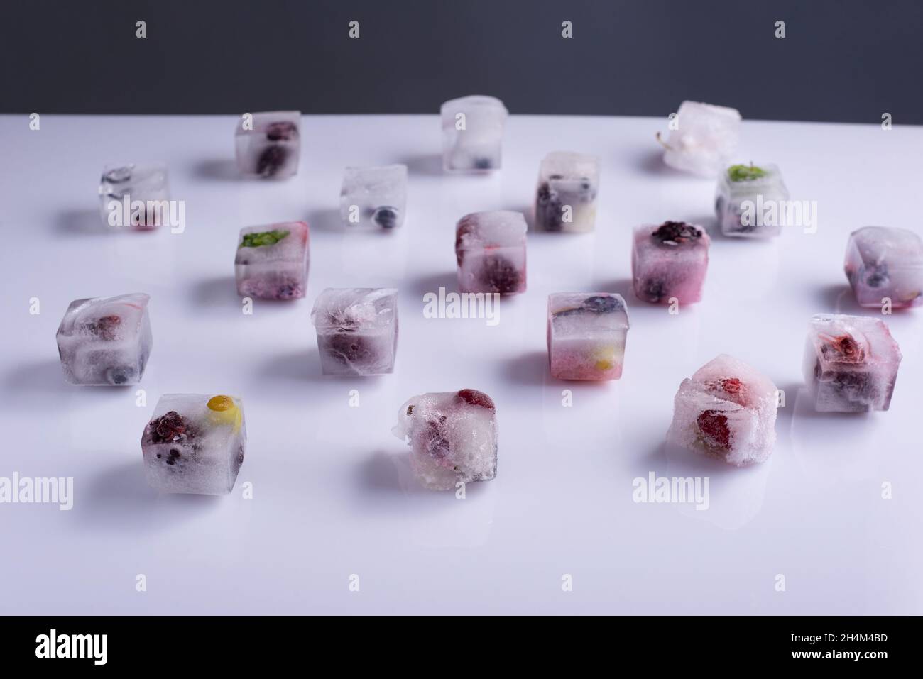 frozen fresh berries fruits in ice cubes on white background. Stock Photo