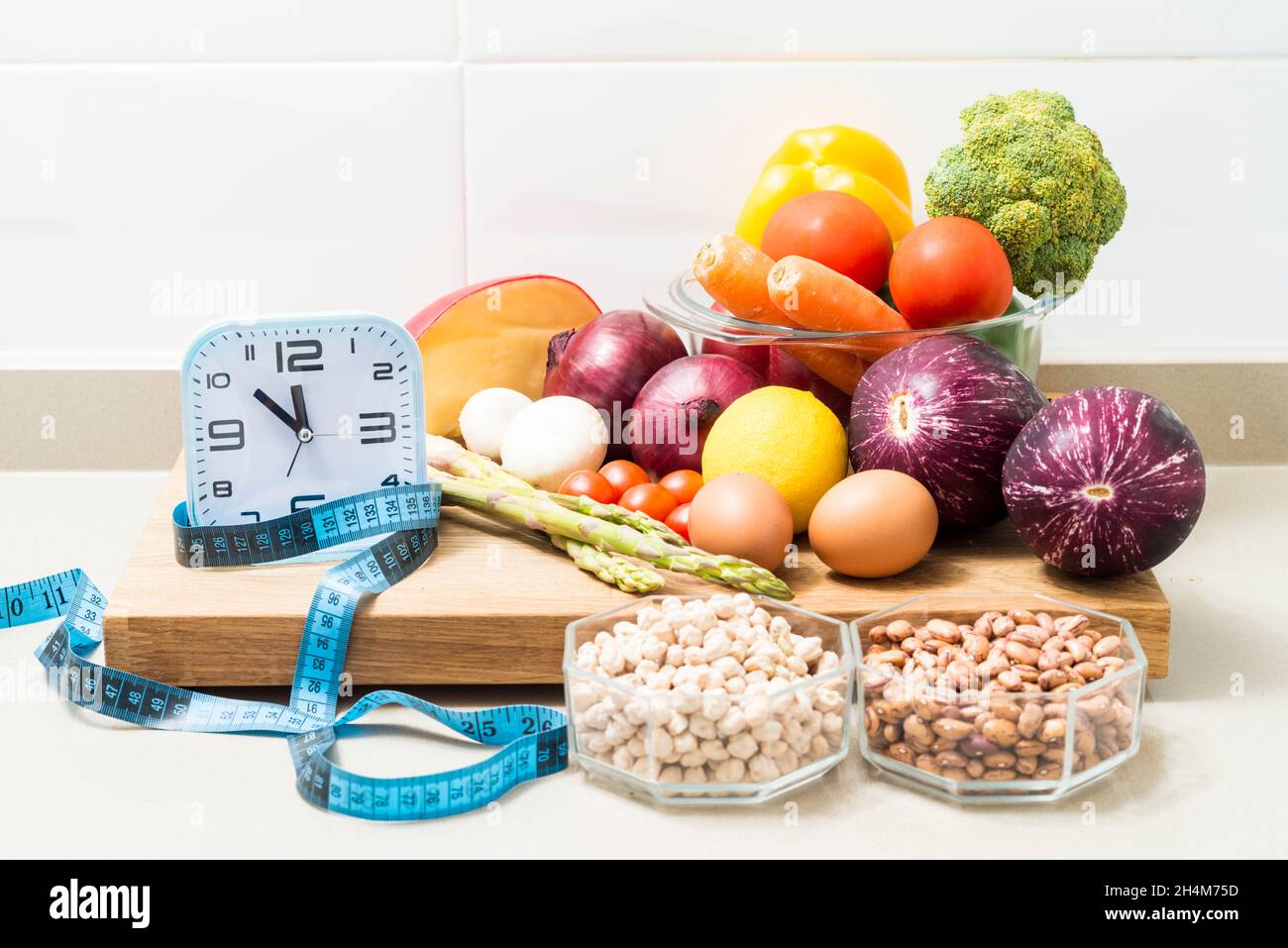 Still life with a clock, a tape measure and healthy food. Conceptual image of intermittent fasting, a diet with benefits such as the regenerative mech Stock Photo