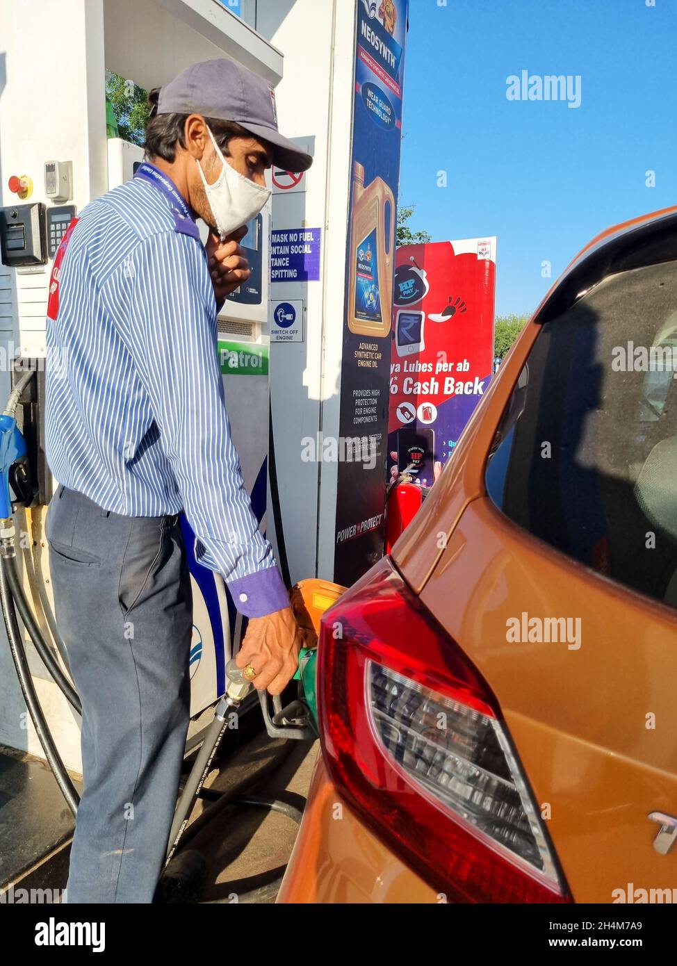 indian man at fuel station filling gas petrol diesel into an orange car