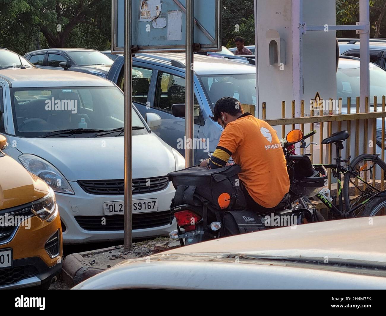 Swiggy Rider Swiggy food delivery rider takes a break on bike while waiting for ...
