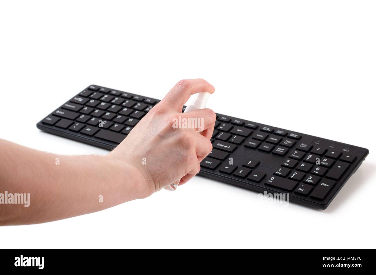 Purity, coronavirus protection and disinfection concept - close up of hand cleaning keyboard with sanitizer spray isolated on a white bsckground Stock Photo