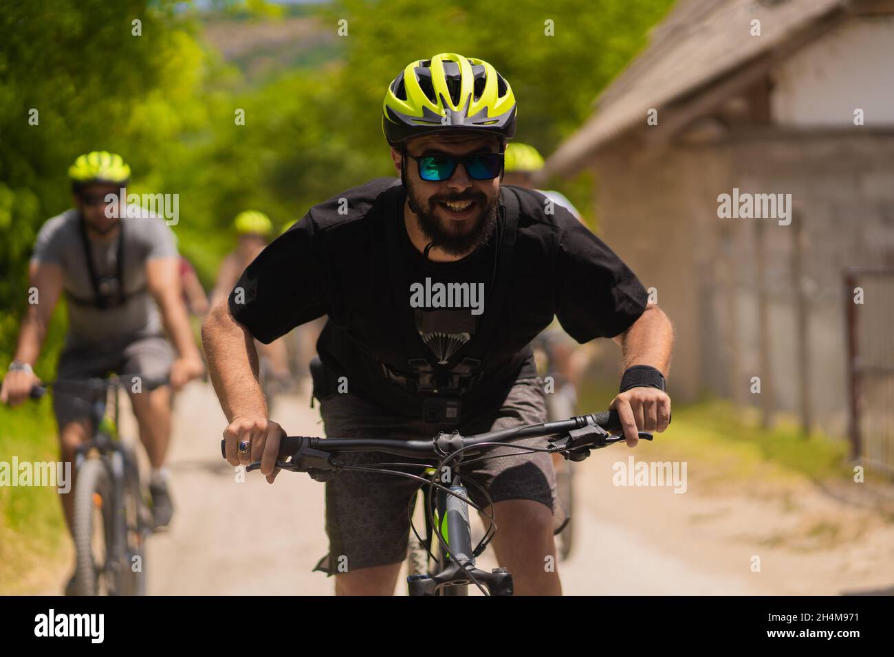 Portrait of adult male riding a bike while being followed from the rest of the group Stock Photo