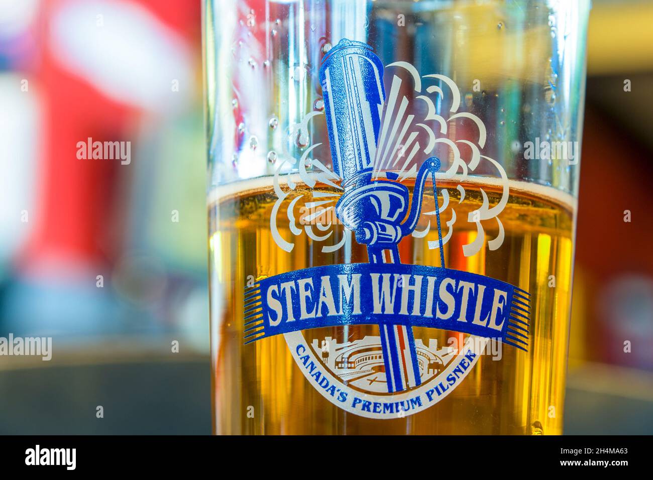 Glass of beer with the Steam Whistle logo seen on a business in Toronto