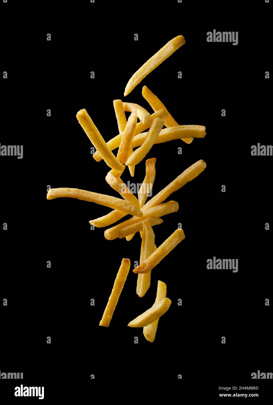 French fries - fried potatoes flying. Fly fastfood isolated on black background. Stock Photo