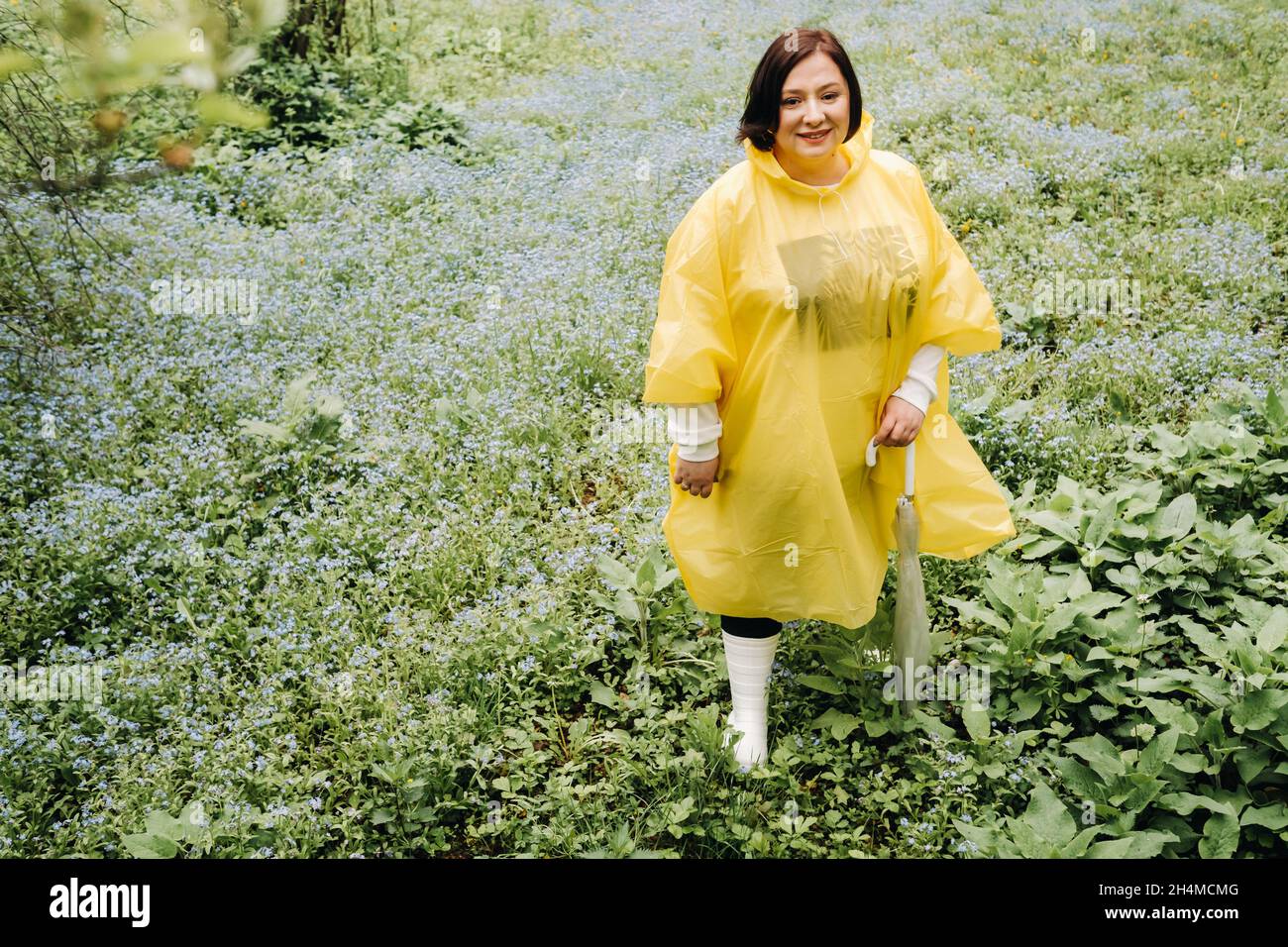 A Woman In A Yellow Raincoat Walks In The Park And Garden In The Summer a-woman-in-a-yellow-raincoat-walks-in-the-park-and-garden-in-the-summer