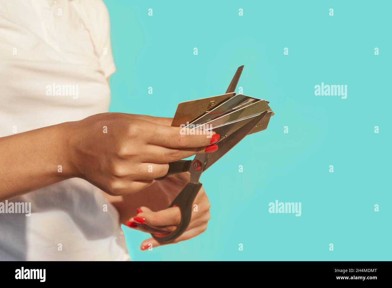 Female hands are cutting a stack of credit cards with scissors Stock Photo