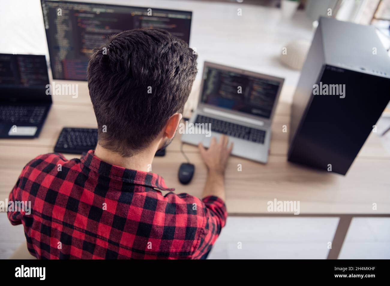 Back rear spine view photo of young man sit desk work code develop software write indoors inside office workplace Stock Photo