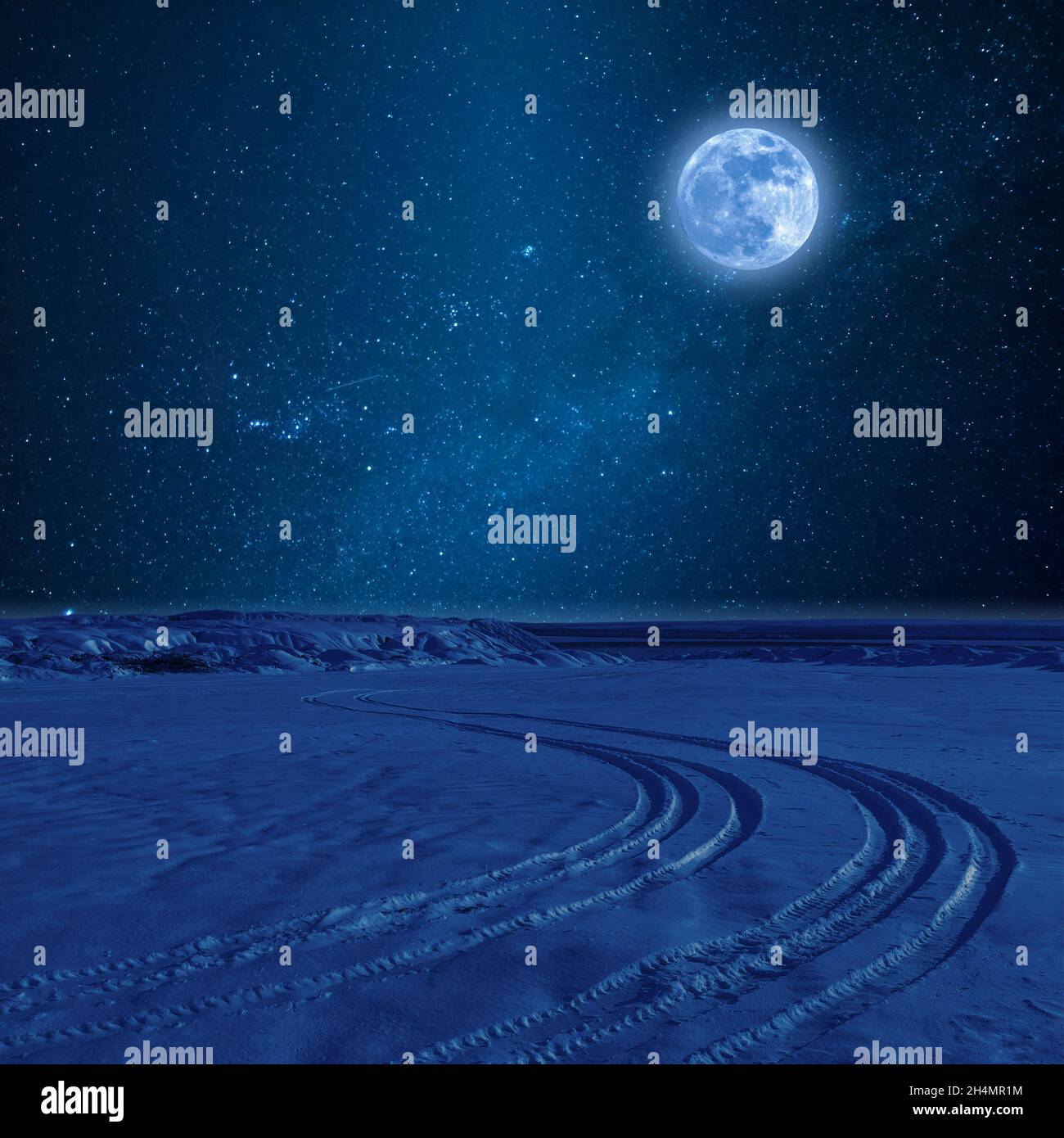 Night landscape with tire trace on snow, stars and full moon in sky Stock Photo