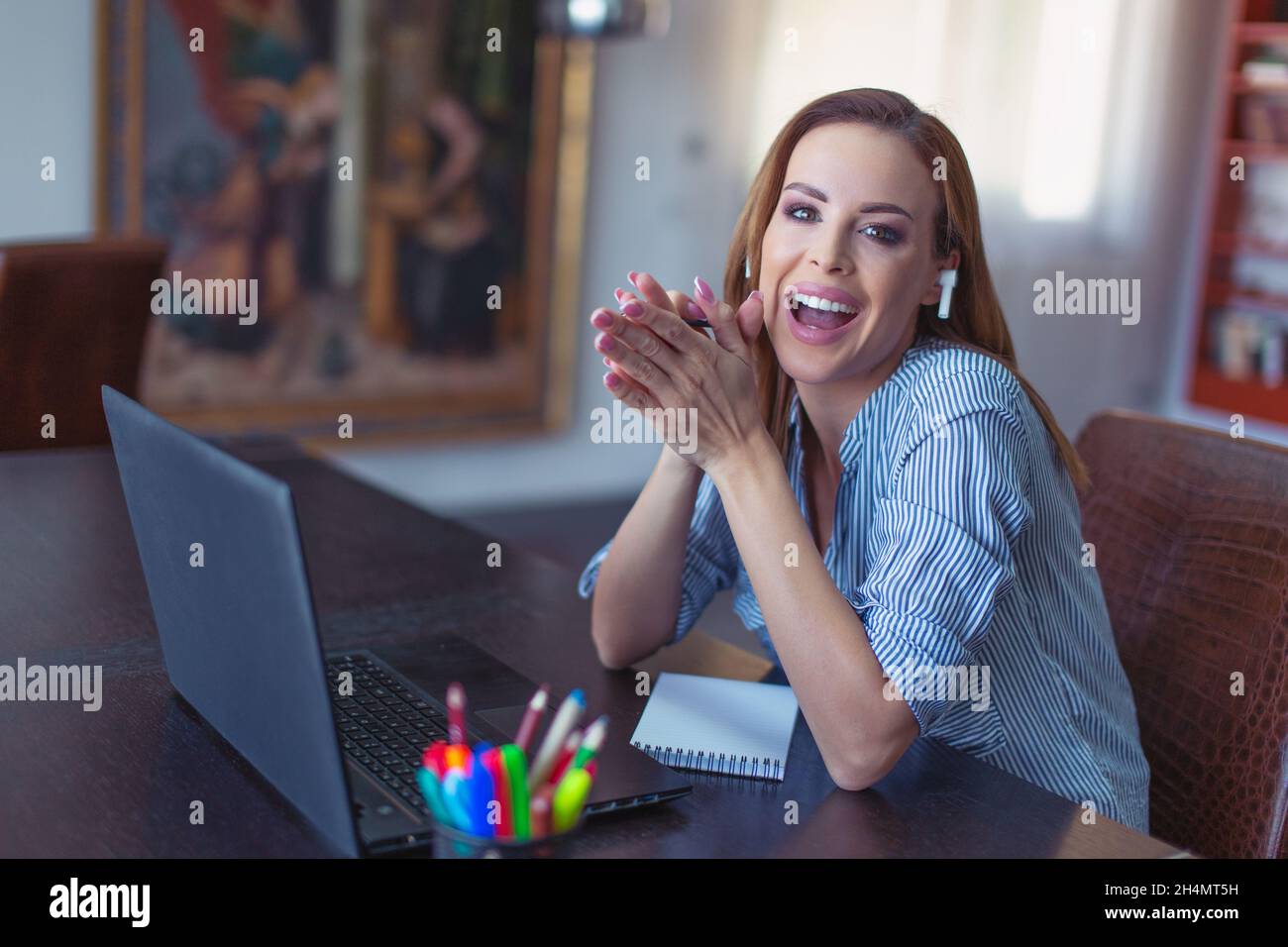 Happy young Caucasian businesswoman laughing at laptop in home office Stock Photo