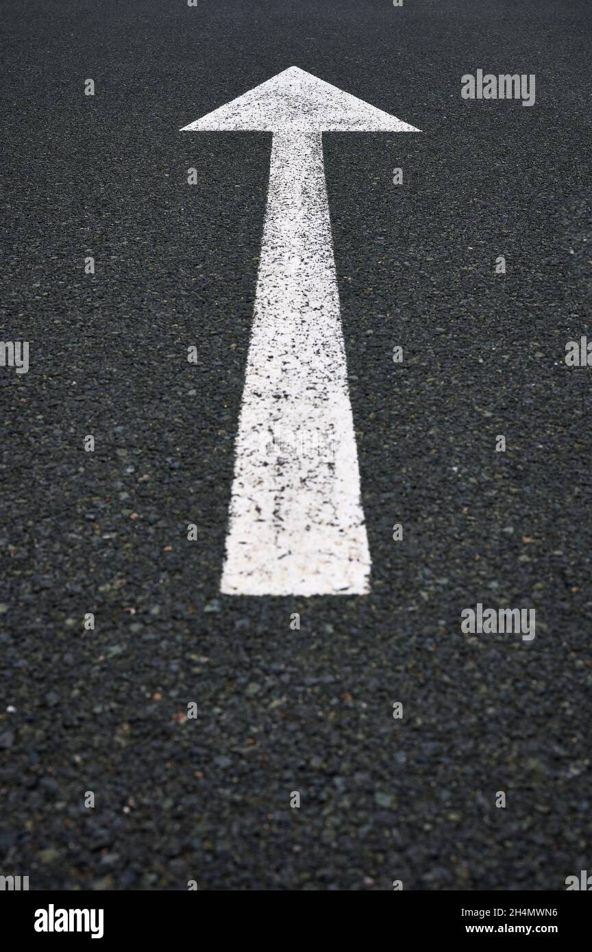 detail of a traffic sign with a white arrow painted on the asphalt. Stock Photo