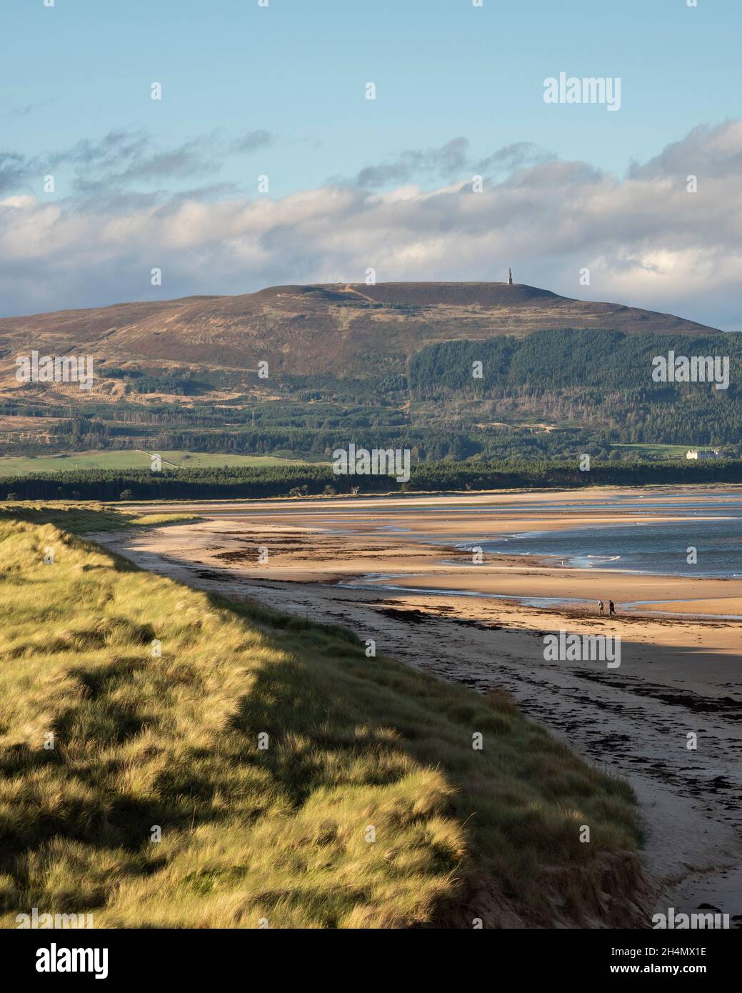 Two people walking by the dunes at Embo beach with Ben Bhraggie beyond. Sutherland, Scotland Stock Photo