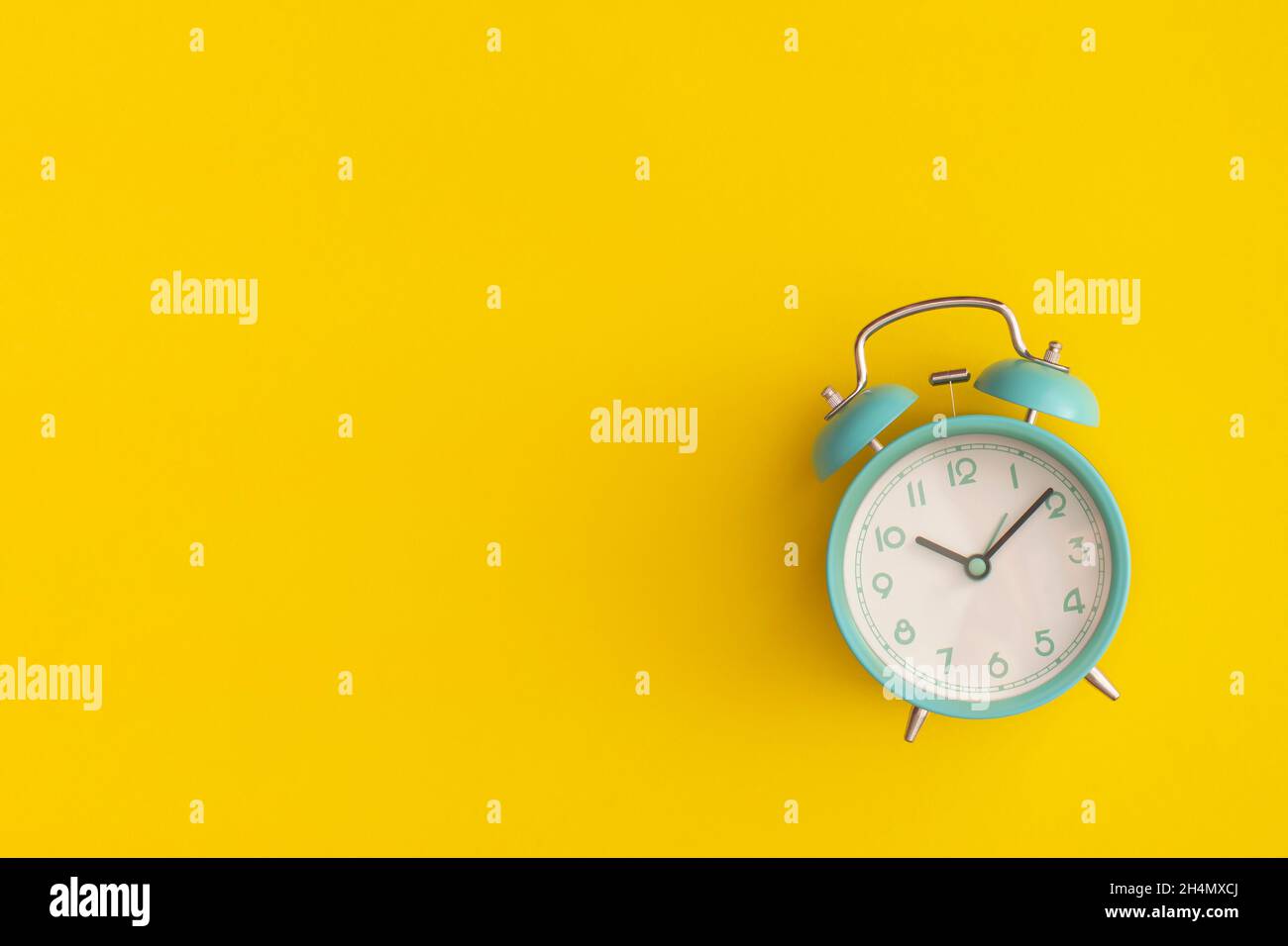 Blue alarm clock on yellow background. Top view with copy space. Flat ...