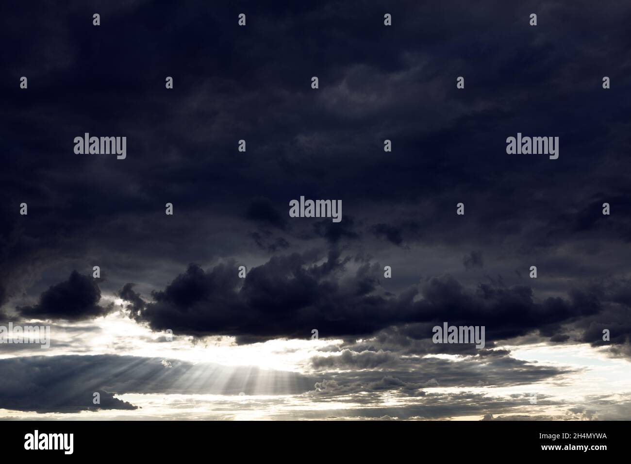 Black clouds with sun rays . Dramatic dark sky with sunlight . Epic heaven Stock Photo