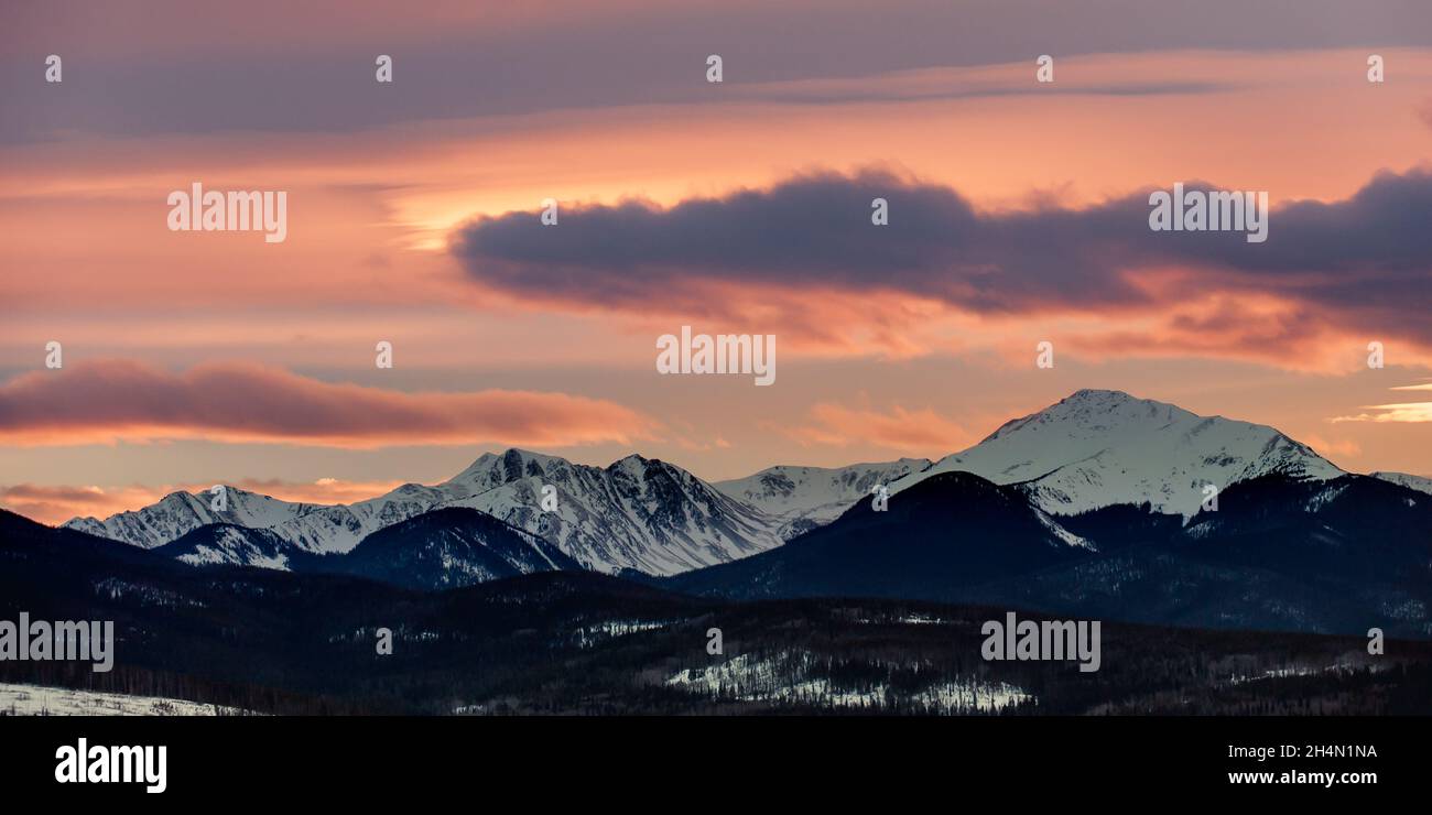 An orange and pink sunset above snowcapped mountains Stock Photo