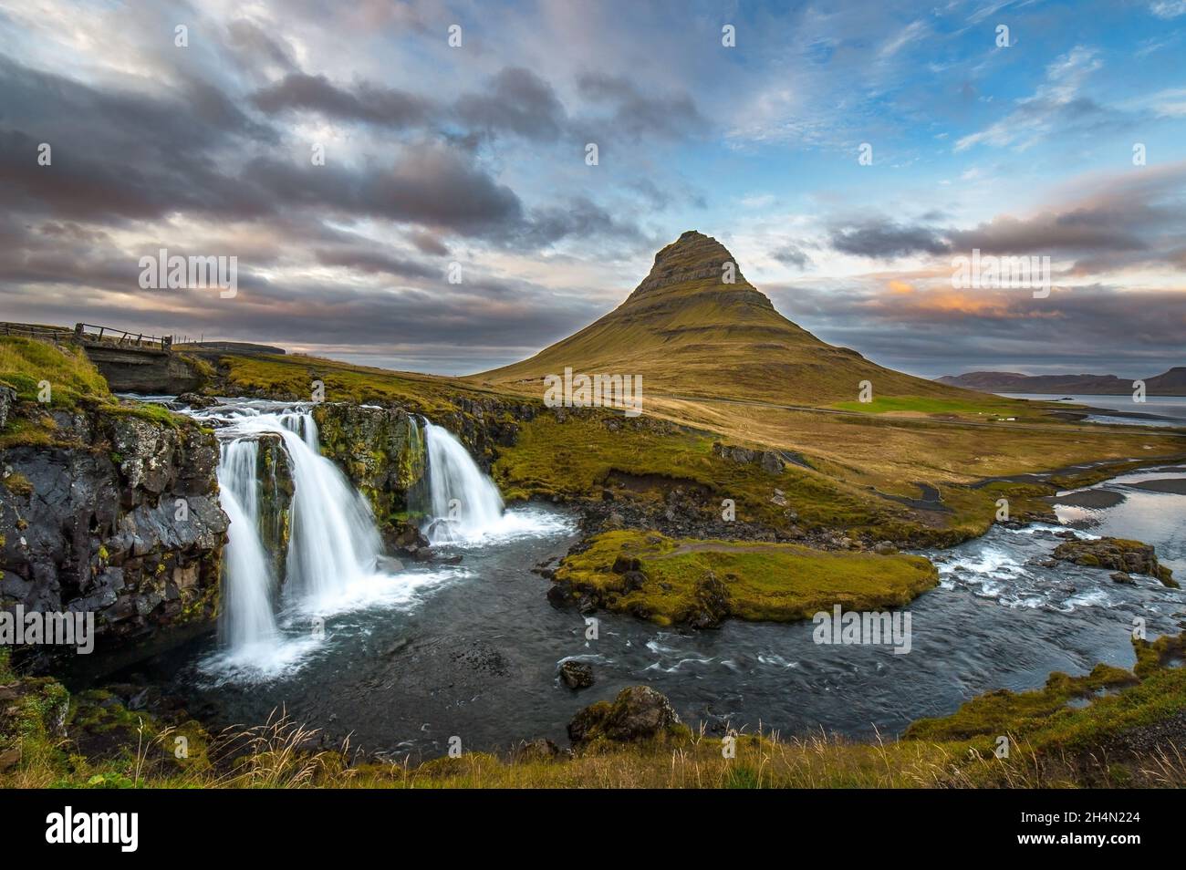 A waterfall (Kirkjufellfoss) and river in front of a mountain (Kirkjufell) and sunset in Iceland Stock Photo