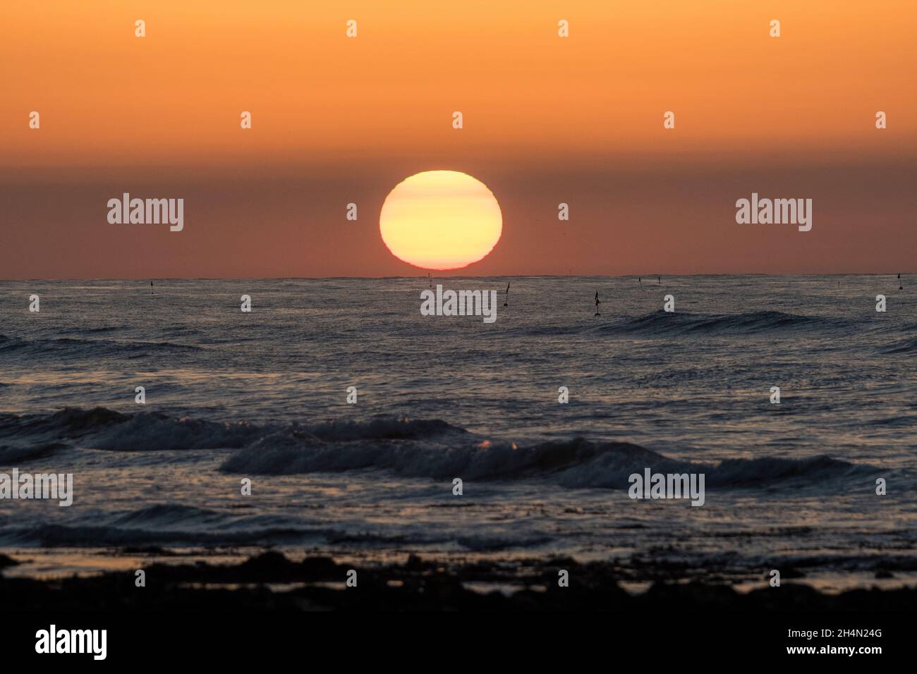 Sun setting over sea at West Runton Beach, Sheringham, North Norfolk Coast Stock Photo