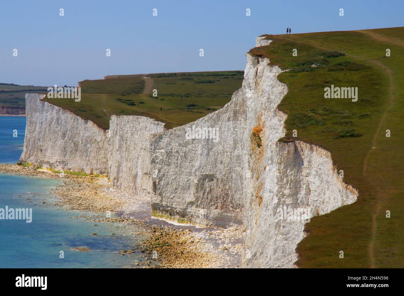 Walkers on the crest of white chalk cliffs and the English Channel on the coast at Seven Sisters, East Sussex, England Stock Photo