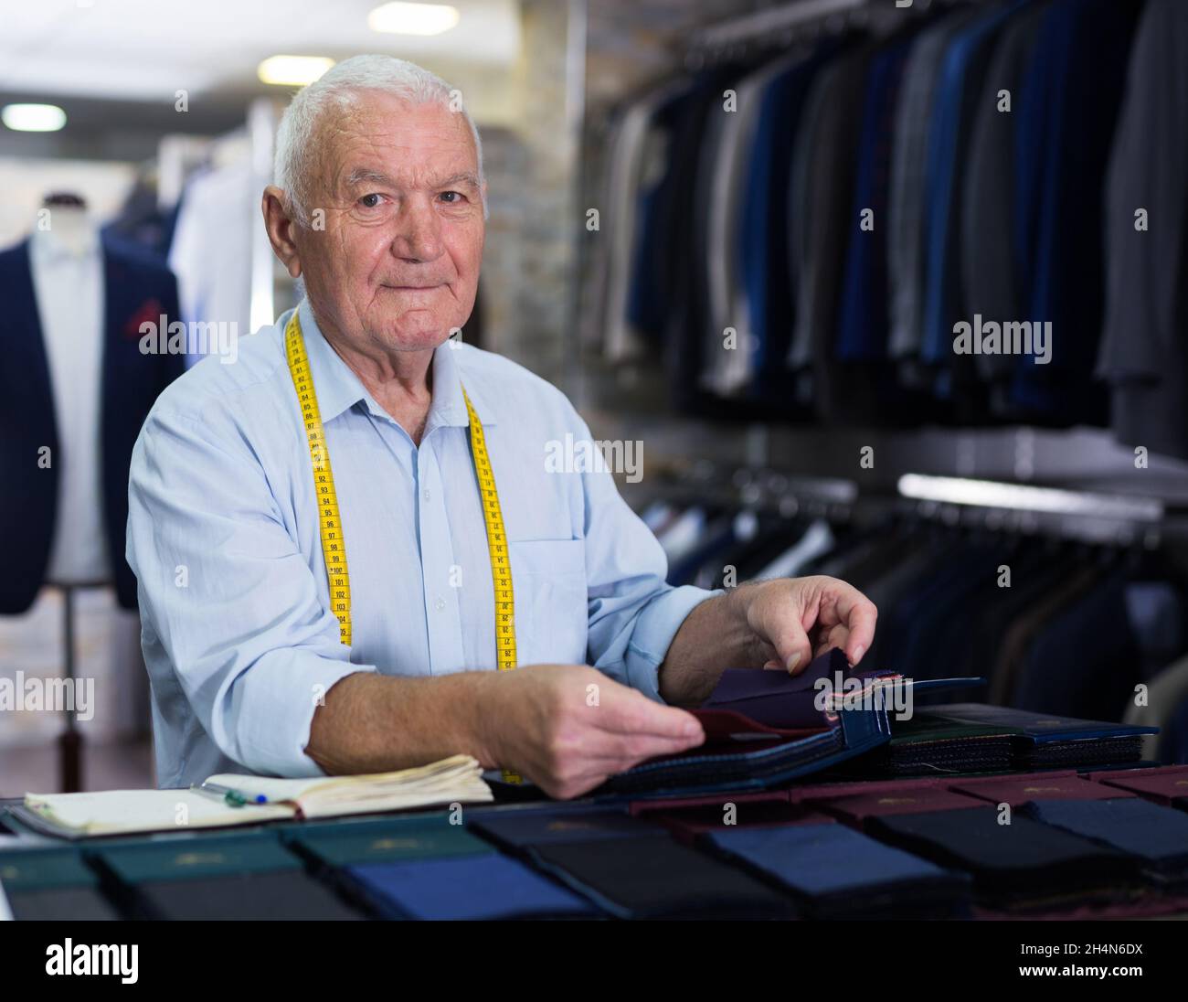 Portrait of an accomplished tailor with samples of fabric in atelier ...