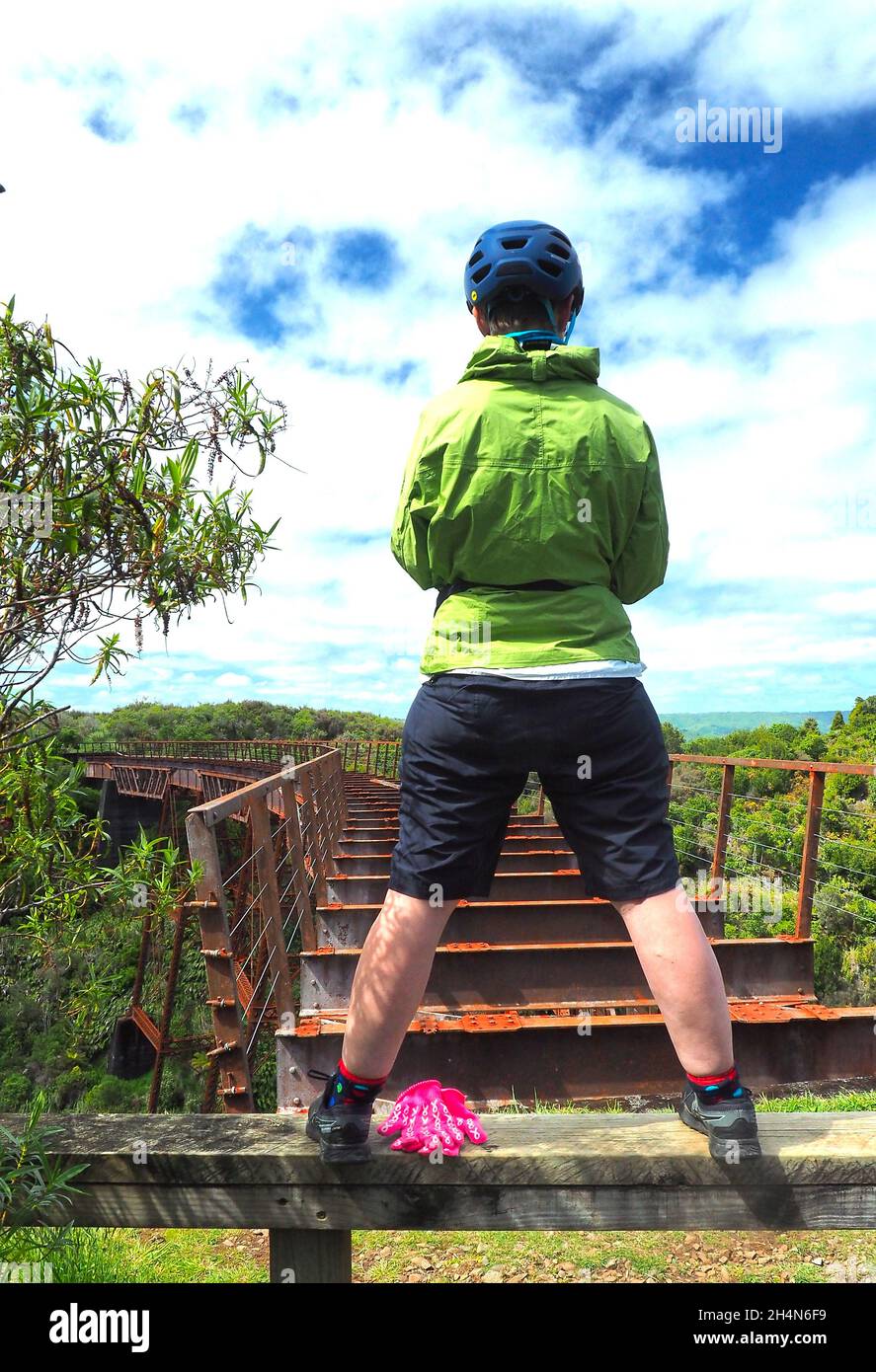 A cyclist uses her phone to photograph the 19th century Taonui rail viaduct, an historic place on the Ohakune Old Coach Road bike trail, NZ Stock Photo