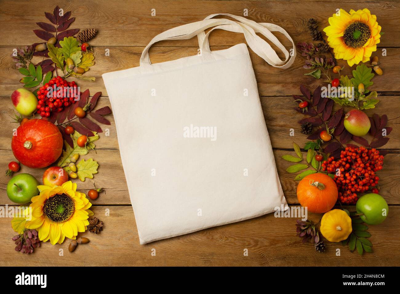 Canvas tote bag mockup with sunflowers, pumpkins and fall leaves. Rustic linen shopper bag mock up for branding presentation Stock Photo