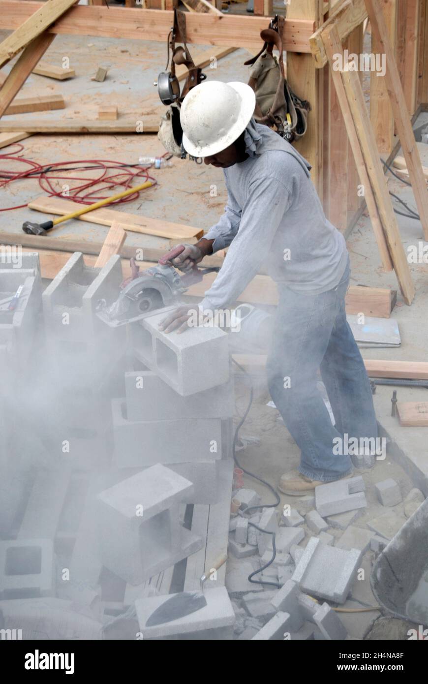 Mason using a circular saw with diamond blade to custom cut structural concrete block Stock