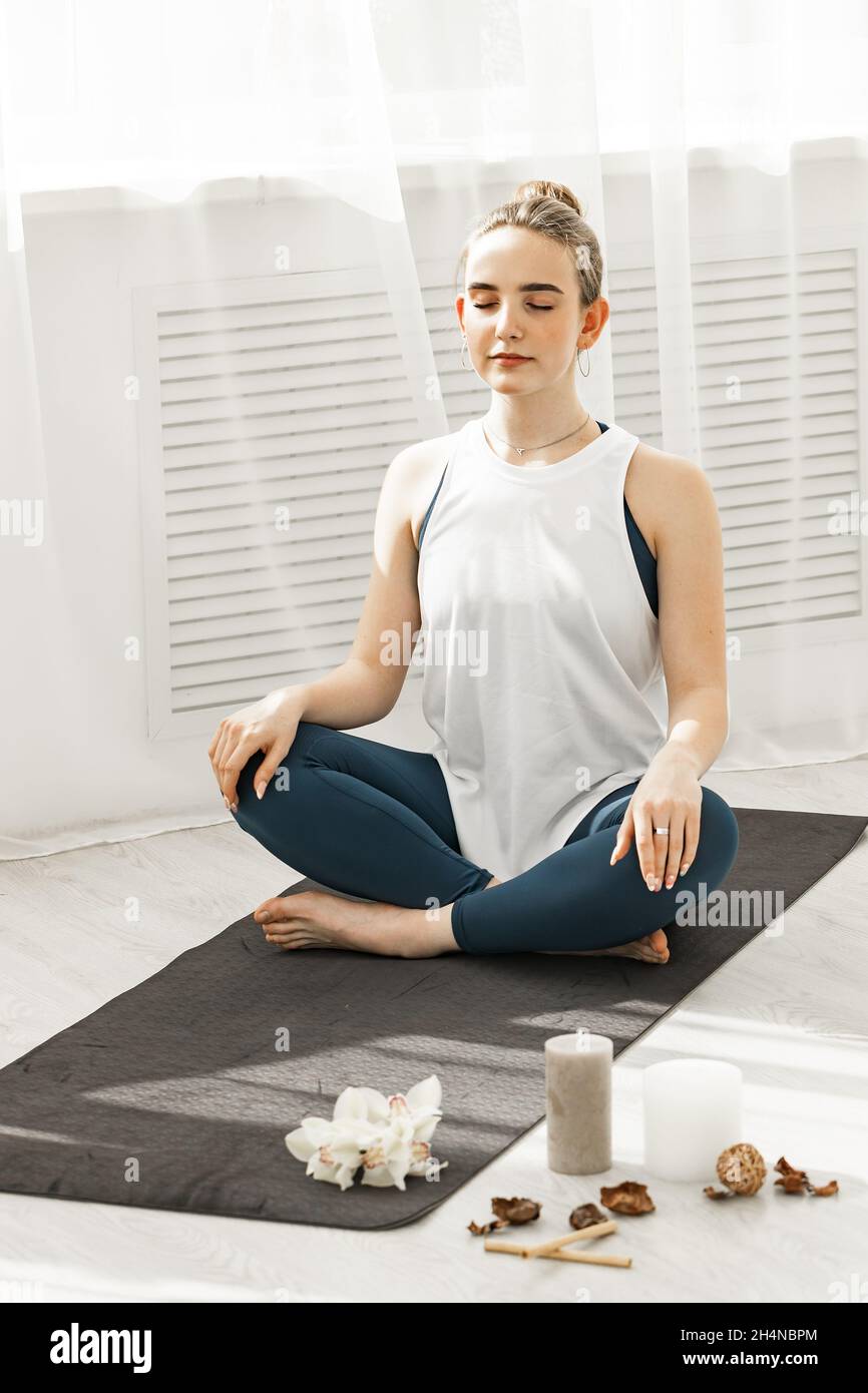 Closeup young sporty fit girl doing hatha yoga on a modern Yoga studio. She sits on the lotus position and meditate. Healthy lifestyle concept. Vertic Stock Photo