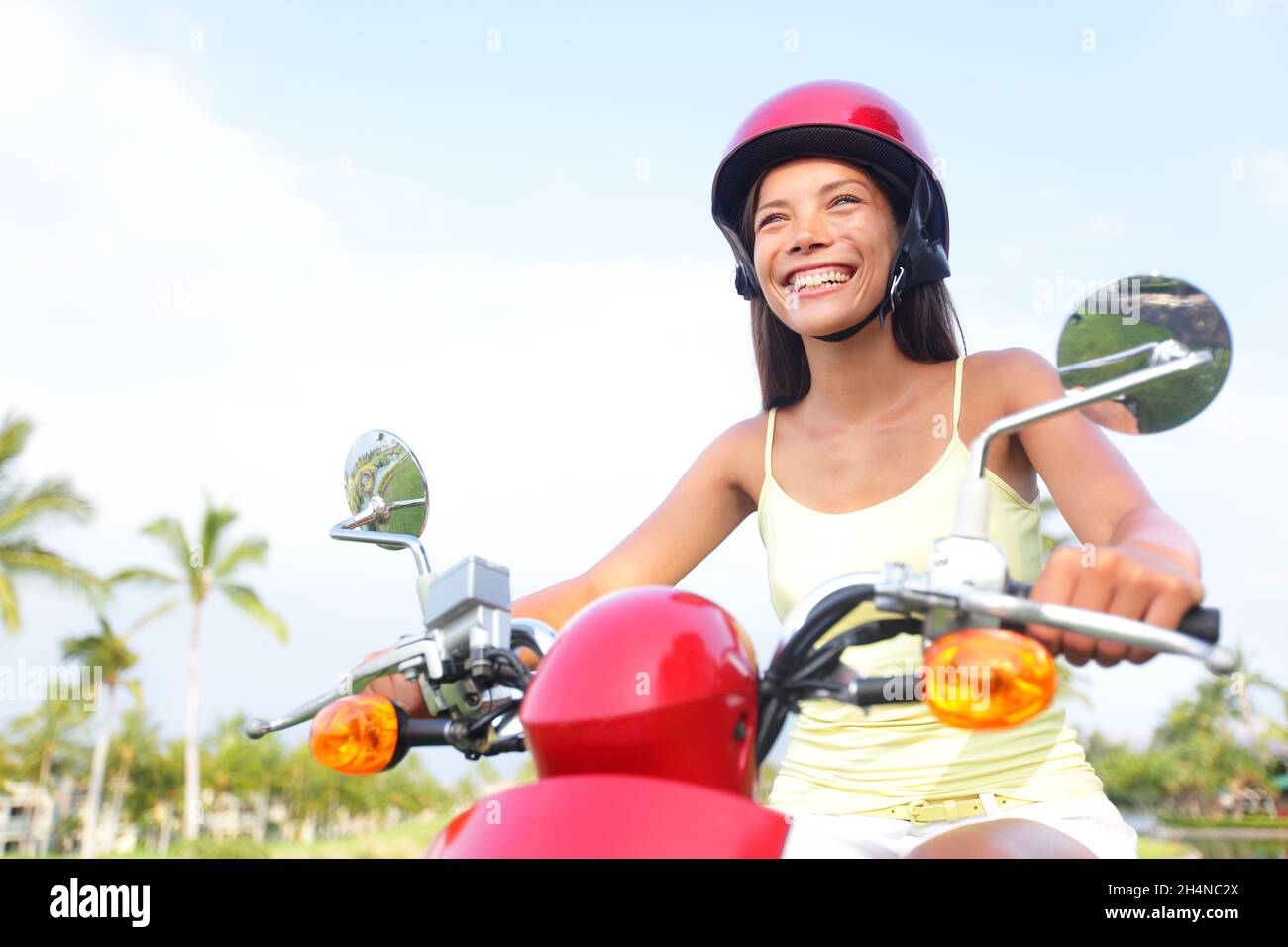 Scooter driving girl riding across town on motorcycle transport. Happy