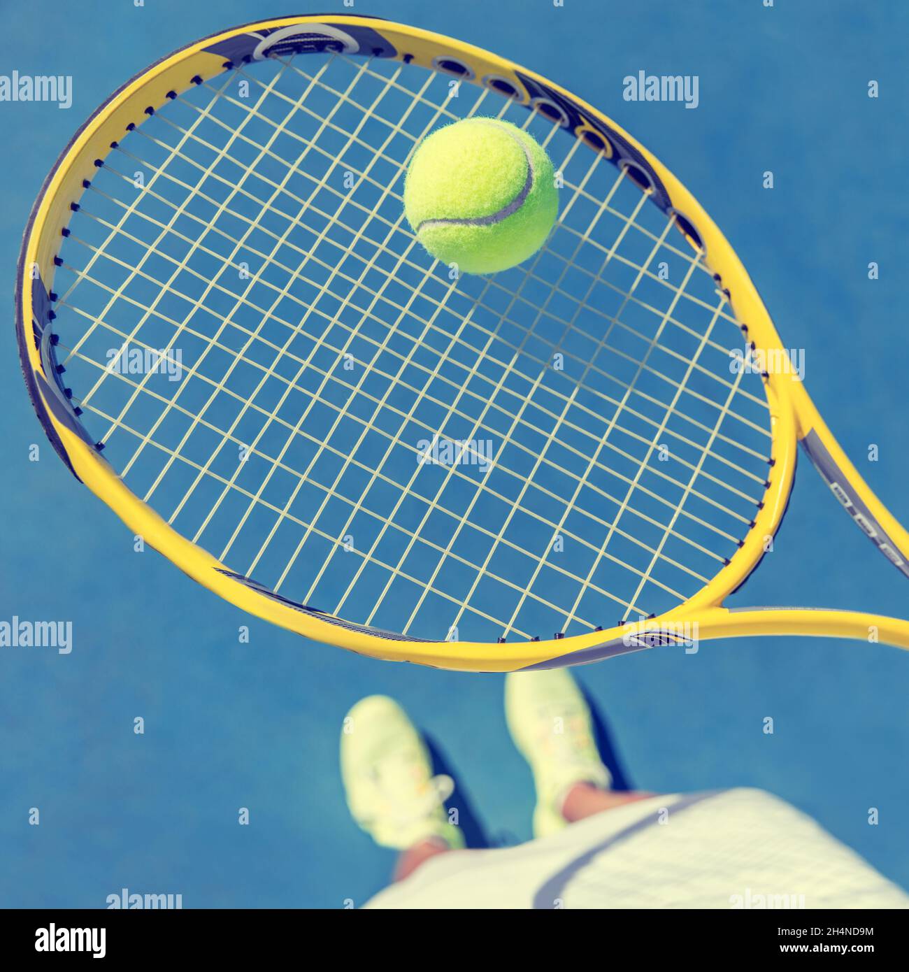 Tennis player girl taking pov selfie of racket and ball ready to play holding racket and showing shoes on blue outdoor tennis court. American hard Stock Photo