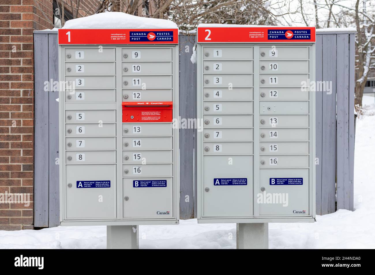 Canada Post mailboxes with red sign in English and French near house in