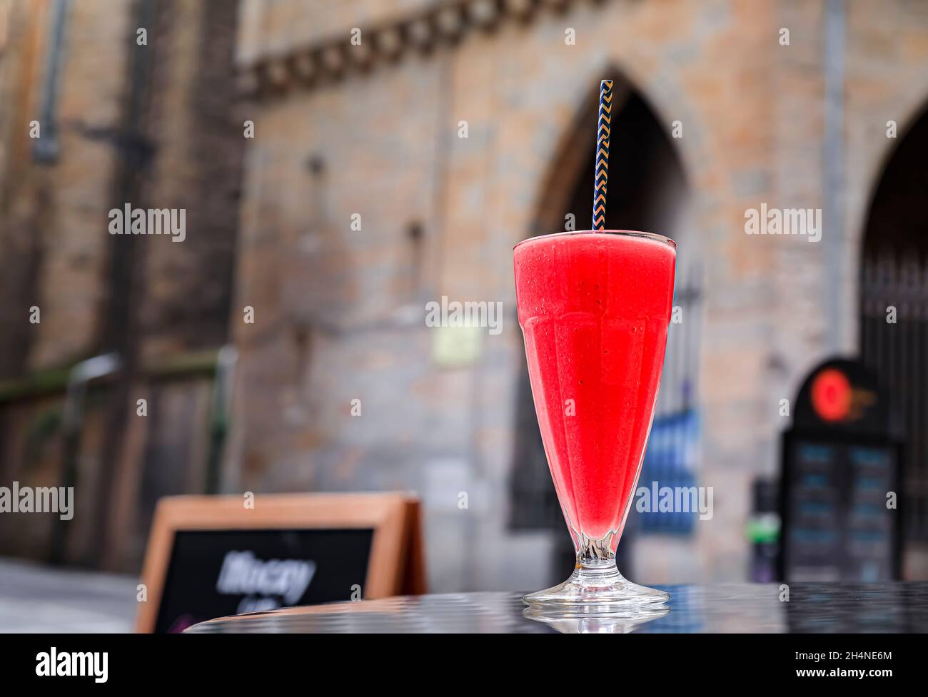 Glass of a fruit smoothie a paper straw made from strawberry and mango