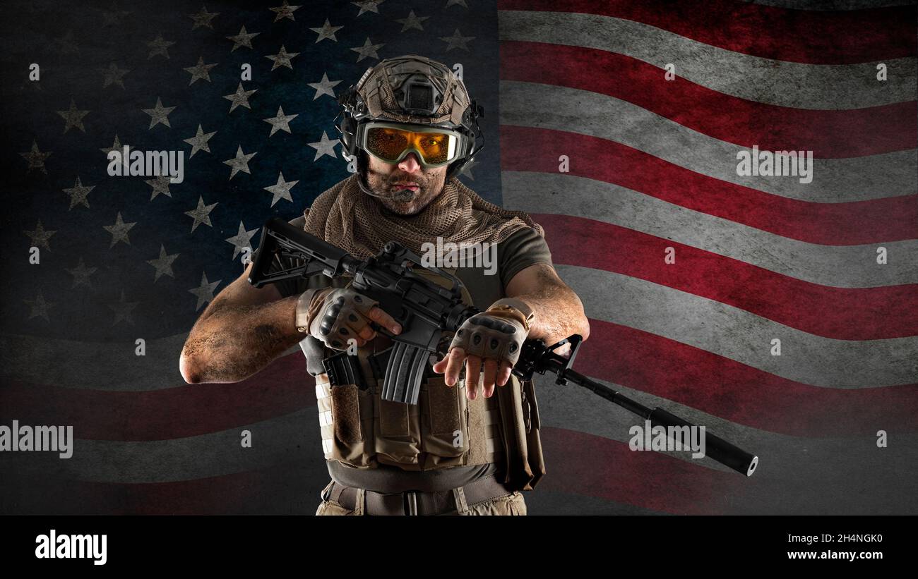 An American infantryman stands against a concrete wall with the American flag. Veterans day concept. Stock Photo
