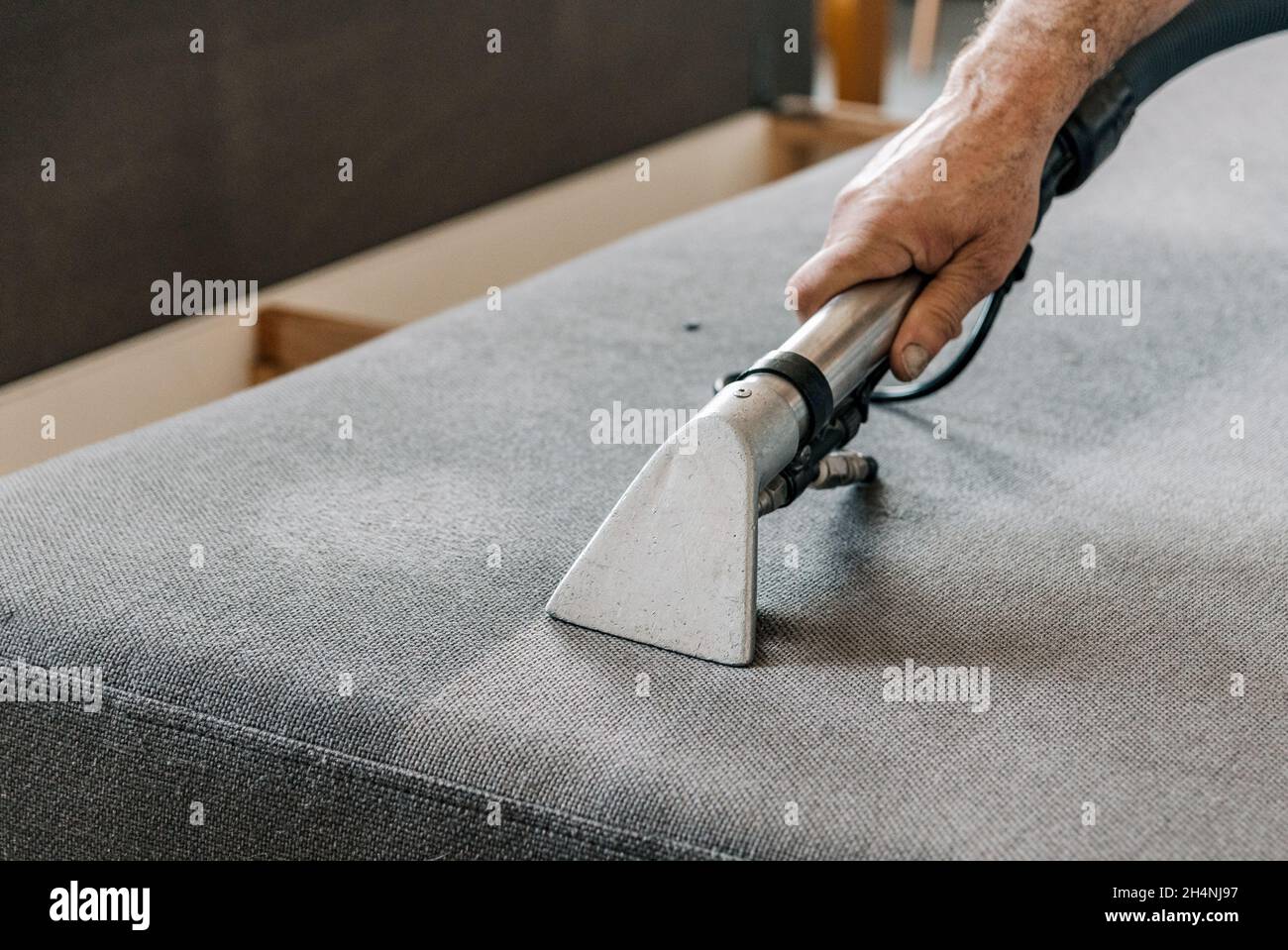 Professional cleaning service deep cleaning sofa at home. Hand holding professional vacuum