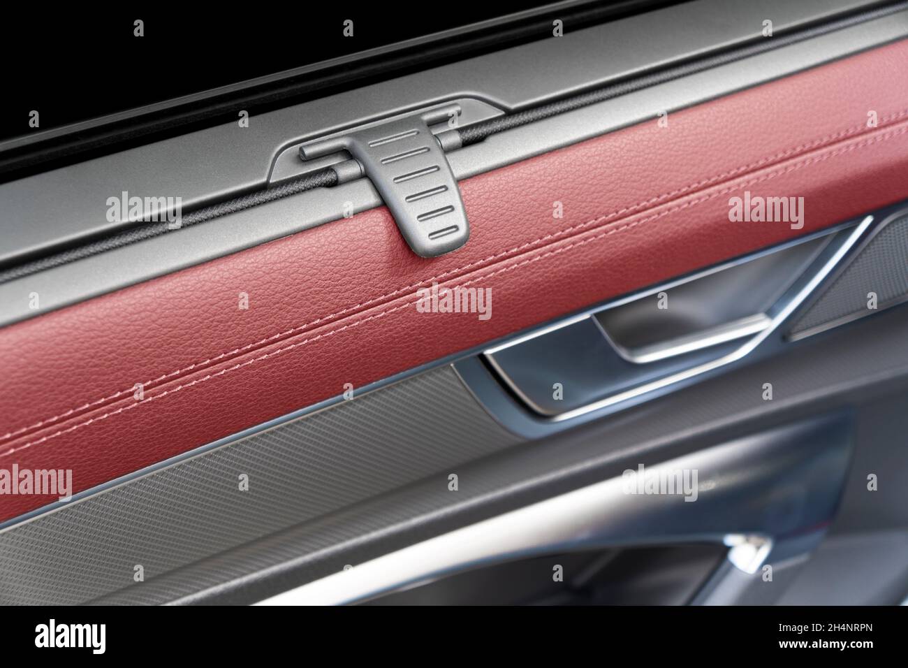 Car door handle with sun shade inside the luxury modern car with red leather texture with stitching. Switch button control. Modern car interior detail Stock Photo