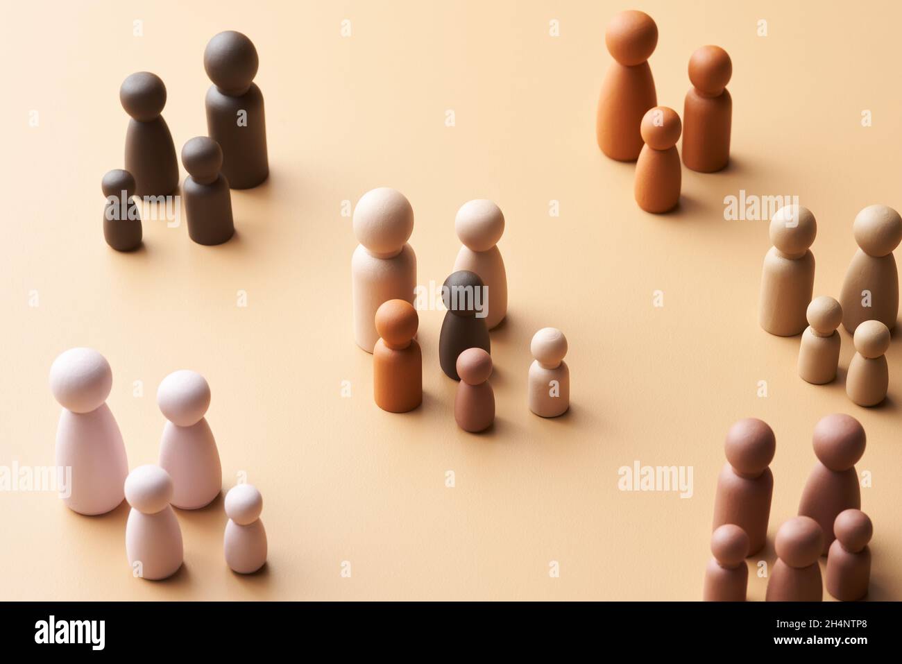 From above figurines of foster parents with multiracial children in modern society against beige background Stock Photo