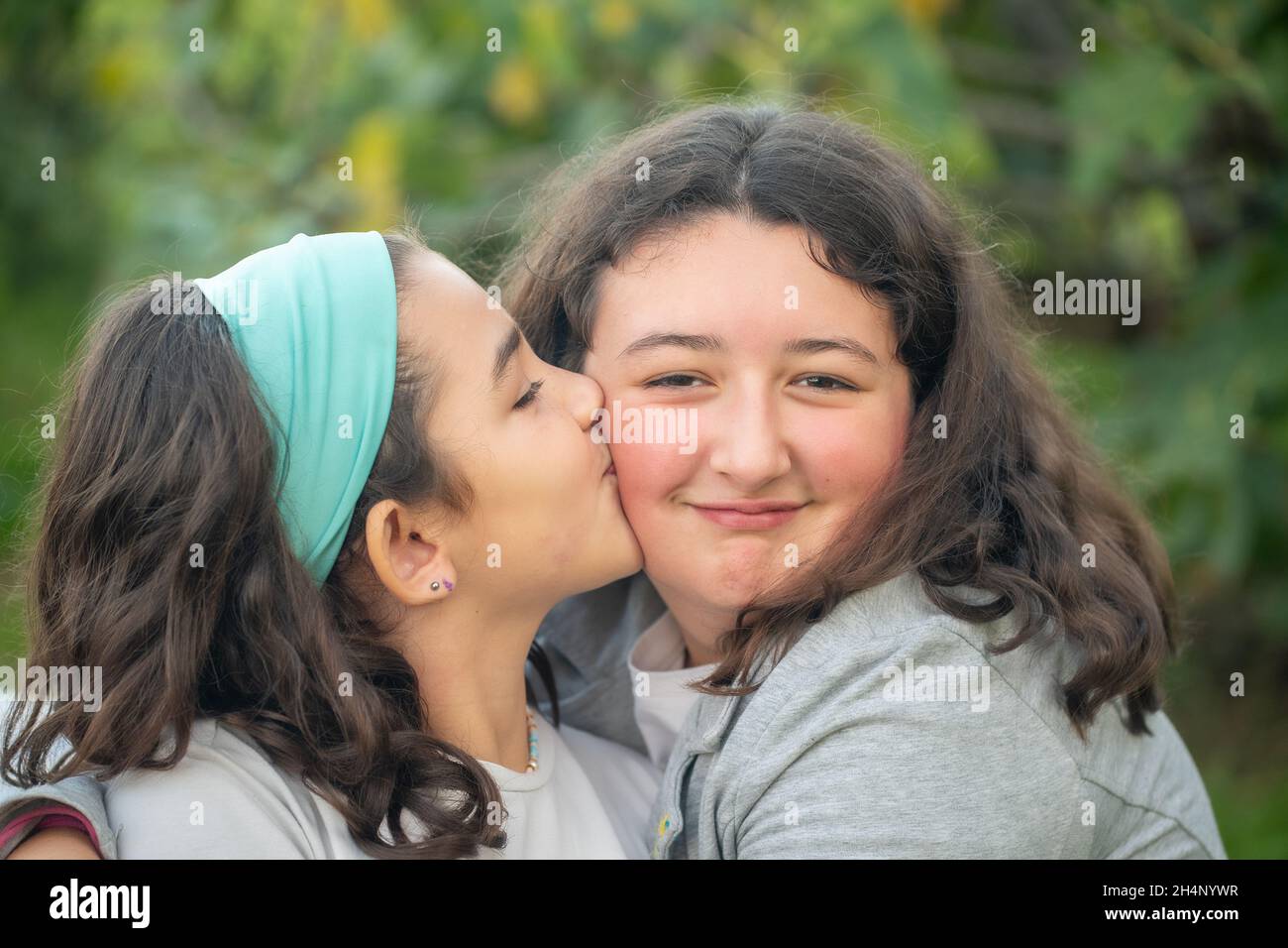 Two young girls embracing and kissing outdoor Stock Photo
